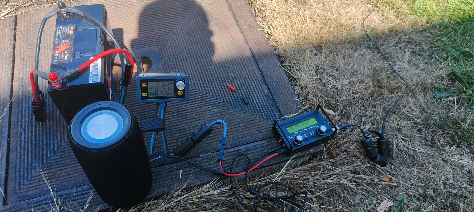 Complete portable station: LiTime battery, buck converter showing 11.50 V, QMX transceiver and Bluetooth speaker